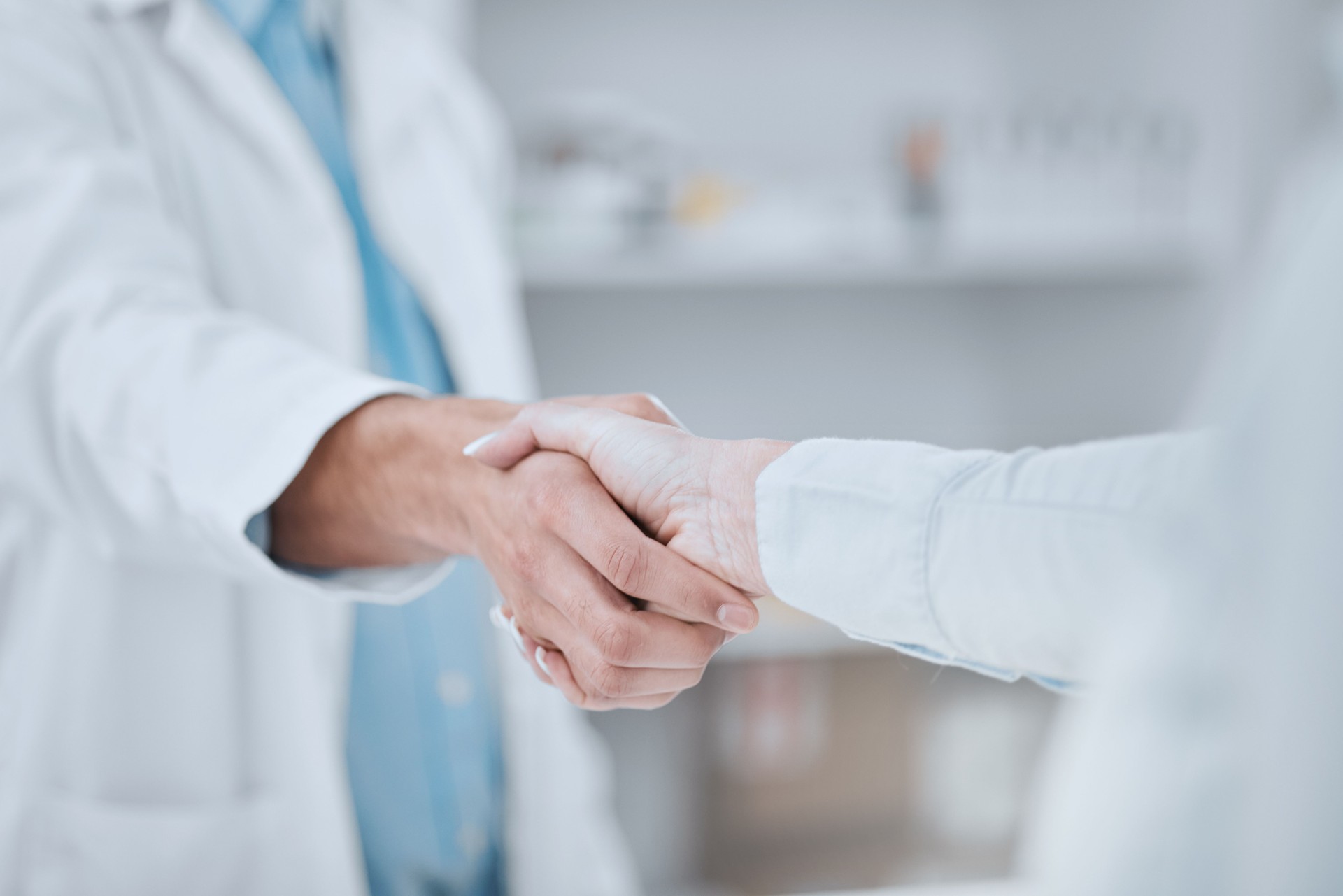 People, pharmacist and handshake in meeting, teamwork or agreement together for deal at pharmacy. Closeup of medical or healthcare team shaking hands in support, unity or thank you at the drugstore